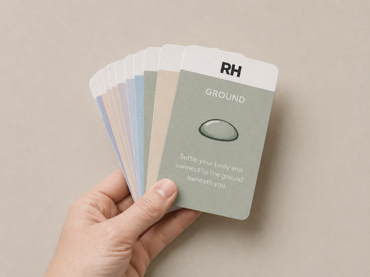 Hand holding a deck of tarot cards with 'RH' branding on a beige background